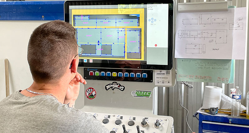 Trabajador delante de la pantalla de una máquina CNC revisando el plano de una encimera de cocina lista para su producción.